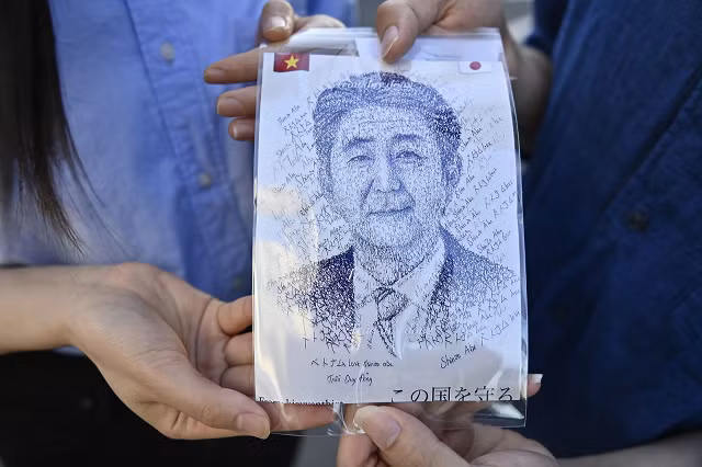 Một cặp vợ chồng đưa ra hình ảnh minh họa của Shinzo Abe khi họ bày tỏ lòng kính trọng trước tư dinh của ông ở Tokyo, Nhật Bản, vào ngày 10/7.