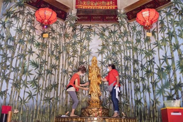 Những người phụ nữ Bali lau một bức tượng để chuẩn bị cho Tết Nguyên đán tại một ngôi chùa ở Kuta, Bali, Indonesia.