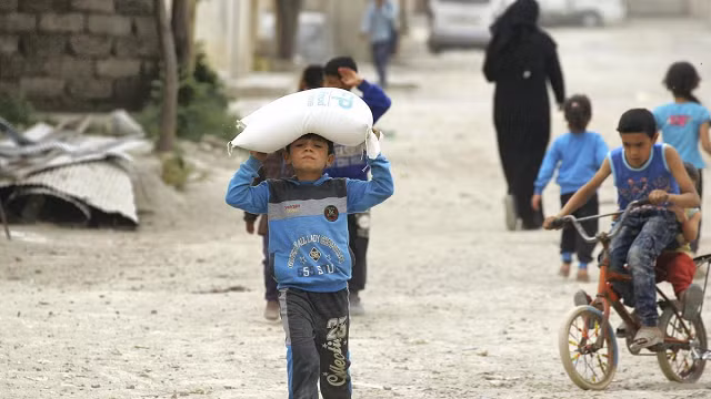 Một cậu bé mang thực phẩm do Chương trình Lương thực Thế giới của LHQ cung cấp ở Raqqa, Syria - về nhà.