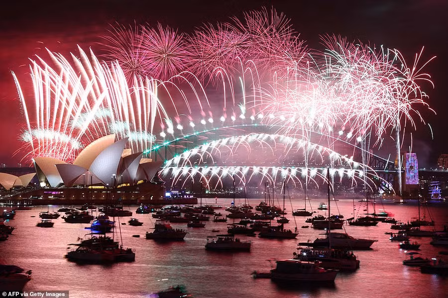 Pháo hoa đêm giao thừa thắp sáng bầu trời Nhà hát Opera Sydney (trái) và Cầu Cảng trong màn bắn pháo hoa ở Sydney vào ngày 1/1/2023