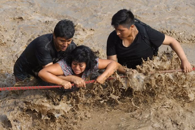 Người dân đi qua một con đường ngập sau một trận lở đất, lụt lội ở Lima, Peru ngày 17/3 Người dân đi qua một con đường ngập sau một trận lở đất, lụt lội ở Lima, Peru ngày 17/3