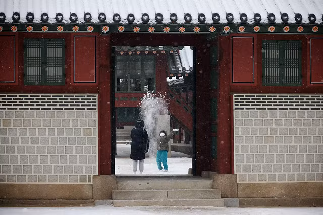Một đứa trẻ chơi trong tuyết tại Cung điện Deoksu ở Seoul, Hàn Quốc.