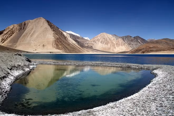 Tên gọi của hồ Pangong Tso mang ý nghĩa là hồ dài, hẹp và đẹp mê hoặc. Hồ nằm ở biên giới giữa Ấn Độ và Tây Tạng, mặt hồ trong vắt và phẳng lặng như một tấm gương khổng lồ, khiến du khách có thể nhìn tới tận đáy.
