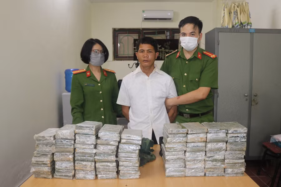 Đối tượng Vàng A Súa cùng tang vật 98 bánh heroin tại cơ quan điều tra. Ảnh: Công an Điện Biên.