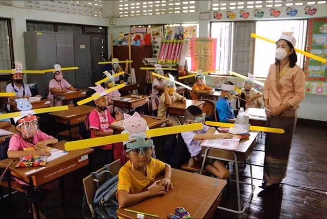 Giáo viên và học sinh đội mũ được thiết kế để giữ khoảng cách tại trường Ban Pa Muad ở Chiang Mai, miền bắc Thái Lan vào ngày 3/7/2020 - Ảnh: AP