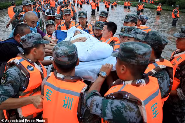 Quân nhân Trung Quốc sơ tán người dân khỏi bệnh viện nơi có khoảng 3.000 người bị mắc kẹt do lũ lụt ở Trịnh Châu, tỉnh Hà Nam, miền trung Trung Quốc.
