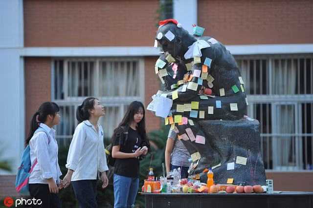 HS viết lời cầu nguyện lên mẩu giấy dán lên bức tượng The Thinker