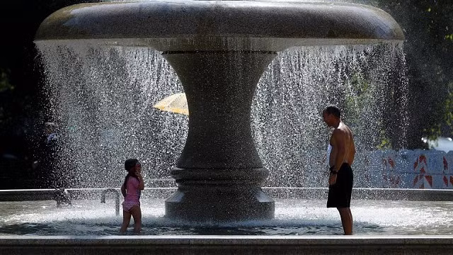 Một người đàn ông và một em bé nhiệt trong đài phun nước vào một ngày hè nóng nực ở Frankfurt,Đức