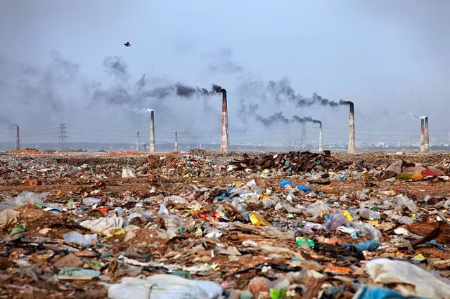 Quang cảnh bãi rác thải rộng lớn bên những ống khói công nghiệp ở Bangladesh.