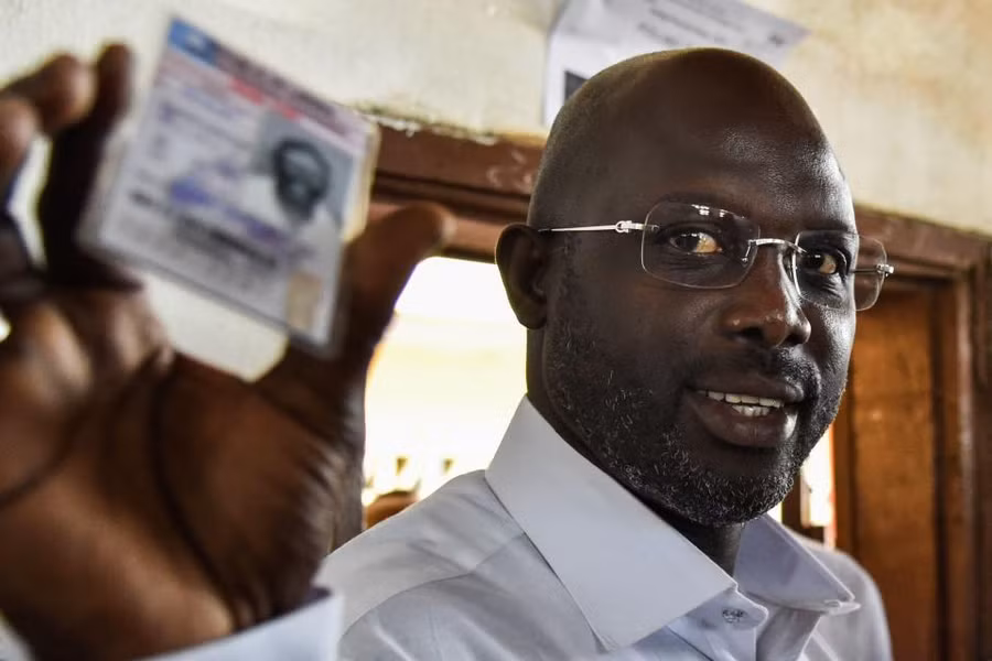 George Weah cầm thẻ căn cước của mình trước khi bỏ phiếu