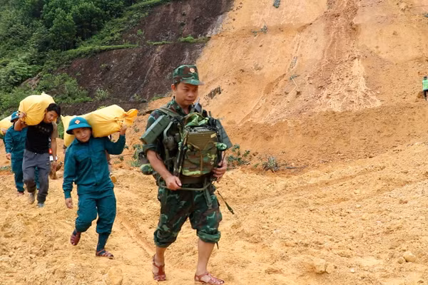 Bộ đội, dân quân tự vệ mang nhu yếu phẩm vượt qua những điểm sạt lở để hỗ trợ Nhân dân.