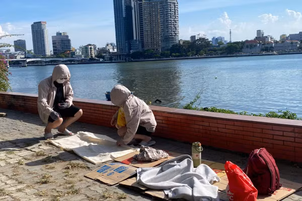 Bìa carton, áo khoác và những vật dụng cá nhân được chuẩn bị sẵn bên sông Hàn cho hành trình chờ đợi xem khai mạc DIFF 2026. 