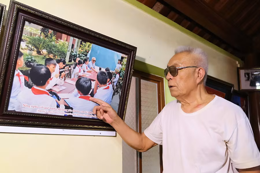 Cựu chiến binh Nguyễn Đăng Khoa bên bức ảnh lưu niệm chụp cùng học trò.