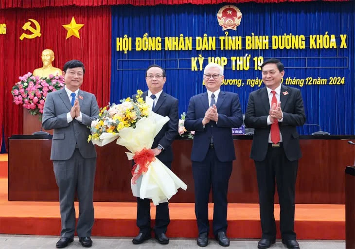 Ông Bùi Minh Thạnh (thứ 2 từ trái qua) nhận hoa chúc mừng từ lãnh đạo tỉnh Bình Dương. (Ảnh: Phương Chi)