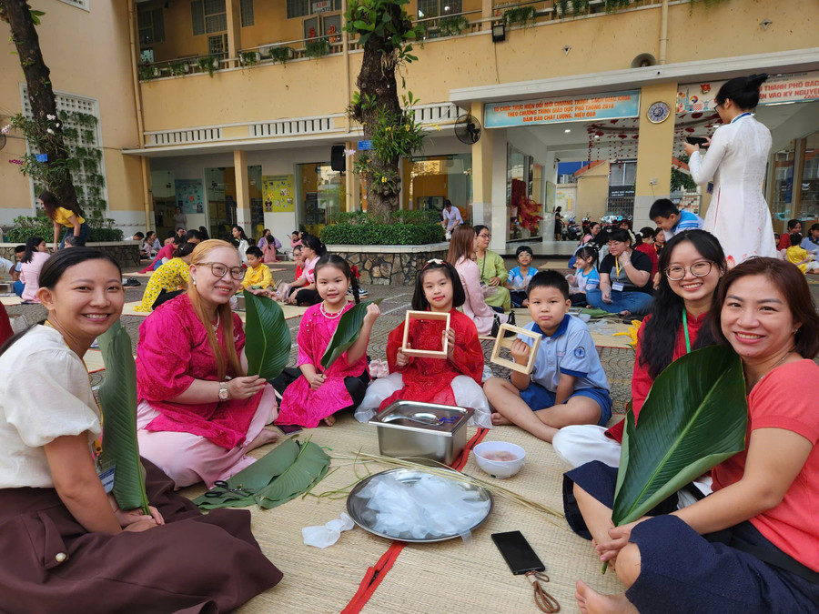 Học sinh, giáo viên và phụ huynh Trường Tiểu học Trần Hưng Đạo cùng nhau gói những chiếc bánh chưng xanh trong ngày hội "Gói Tết-Trao Xuân".