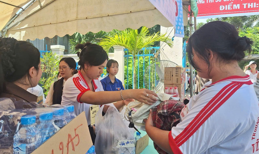 Thanh niên tình nguyện trao lại đồ dùng cá nhân của thí sinh sau giờ thi. Ảnh: Trọng Nhân. img-20250626-104328.jpg