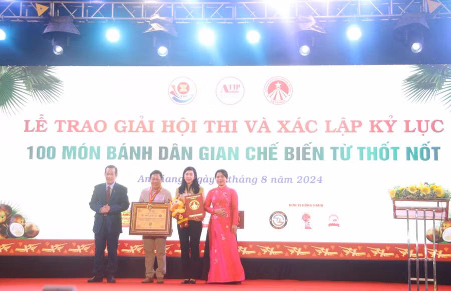 Đại diện Tổ chức kỷ lục Việt Nam trao bằng Xác lập kỷ lục "100 món bánh dân gian chế biến từ thốt nốt". (Ảnh: Trọng Nhân).