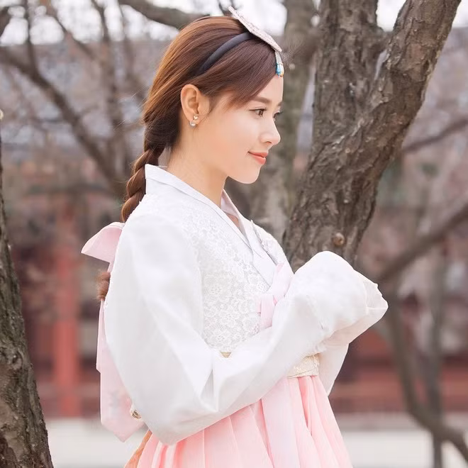 Tóc thắt bím rất quen thuộc với hội tóc dài, bao gồm cả Midu. 8X thắt bím tóc đơn giản, đồng hợp sử dụng phụ kiện cài tóc và dây ruy băng hồng điệu đà.