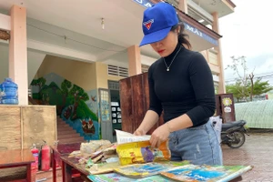 Giáo viên lựa những quyển sách còn sử dụng được phơi khô để học sinh học tập.