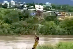 Máy bay không người lái đưa cháu bé bị mắc kẹt giữa dòng nước chảy siết vào bờ. Ảnh cắt từ clip.