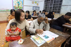 Giáo viên vừa bế con giúp học viên vừa dạy chữ.