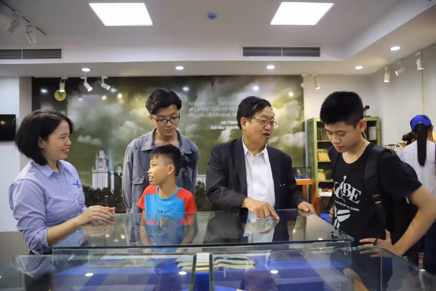 GS.TSKH Trần Duy Quý chỉ cho cháu nội cuốn vở ghi chép tự học ngoại ngữ của một nhà khoa học.