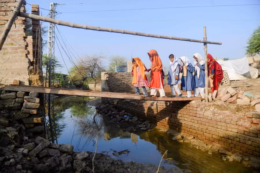 Trẻ em Pakistan băng qua một 'cây cầu' tạm để đến trường.