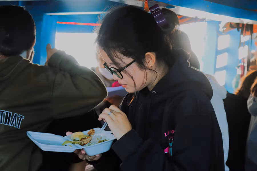 Trên đò, các em tranh thủ ăn trước khi vào lớp học. Ảnh: Bùi Vân