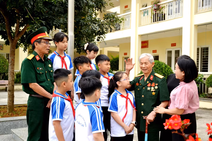 Ông Bế Văn Sâm (người giơ tay) đang kể chuyện lịch sử cho các em học sinh.