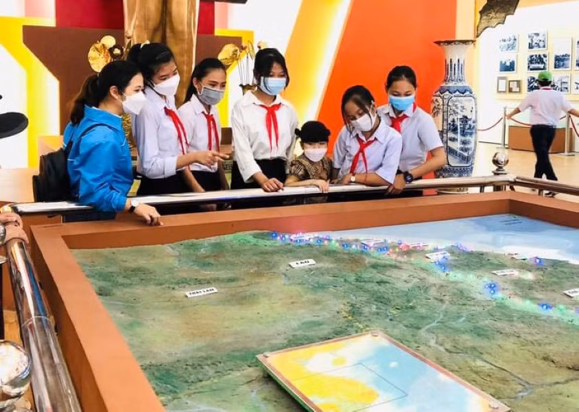 Cô Hứa Thị Nguyệt Quế (áo sẫm) Tổng phụ trách Đội Trường THCS Nguyễn Huệ cùng học sinh tham gia hành trình về “Địa chỉ đỏ” tại Nhà trưng bày khu An ninh khu V.