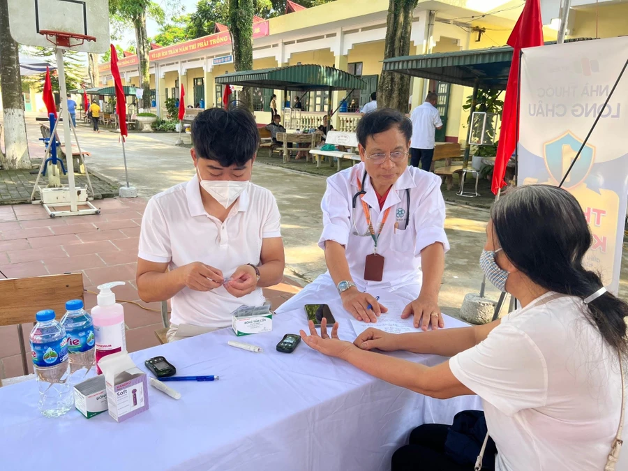 Bác sĩ, TS Lê Quang Minh (giữa), Trưởng khoa điều dưỡng, Trường CĐ Hà Nội khám bệnh cho người dân. 