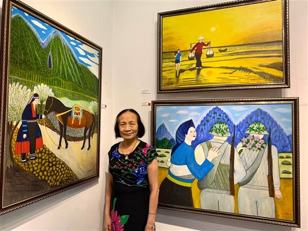 Bà giáo Nguyễn Ngọc Dậu bên những tác phẩm của mình tại triển lãm tranh. 
