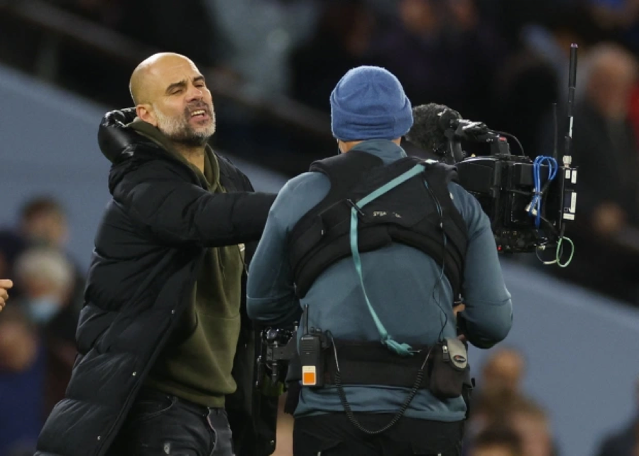 Guardiola đẩy máy quay của phóng viên đi khi tiếng còi mãn cuộc vang lên. Guardiola đẩy máy quay của phóng viên đi khi tiếng còi mãn cuộc vang lên.