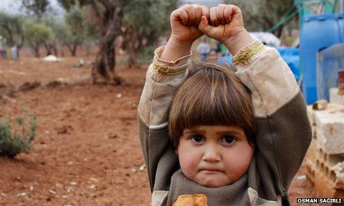 Bé Hudea nhầm máy ảnh là khẩu súng nên sợ hãi giơ tay đầu hàng khi trông thấy phóng viên ảnh chụp mình. Ảnh: Osman Sağırlı. tho1-2262-1427789711.jpg