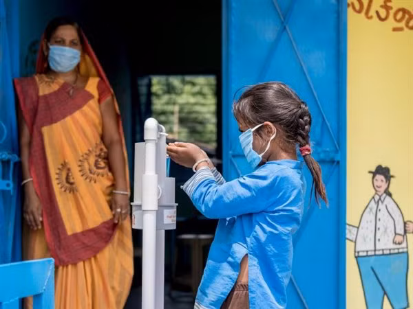 Học sinh Ấn Độ sát khuẩn tay trước khi vào trường học.