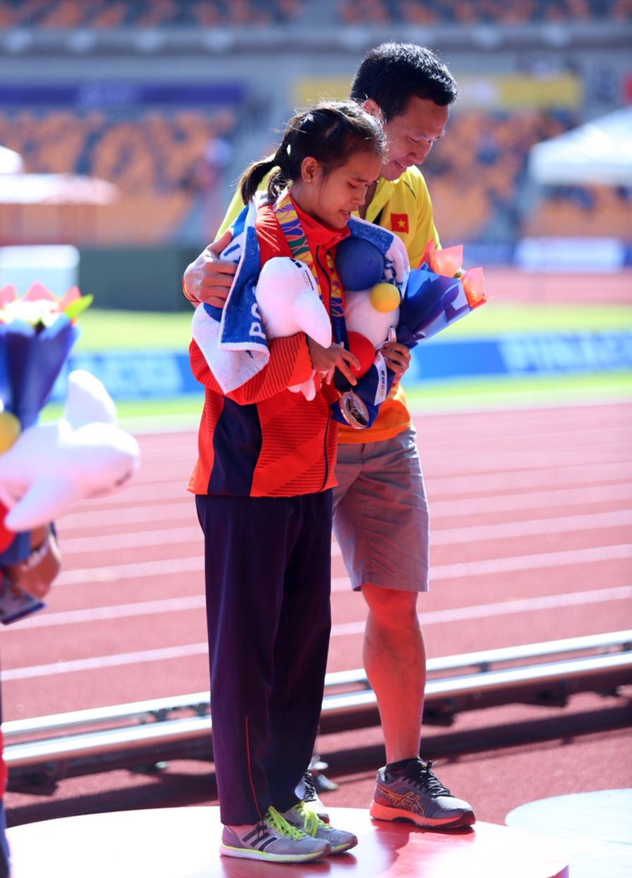 Huấn luyện viên Trần Văn Sỹ dìu học trò Phạm Thị Hồng Lệ trên bục nhận giải Huy chương Đồng nội dung marathon nữ SEA Games 30 – 2019. Ảnh: INT.