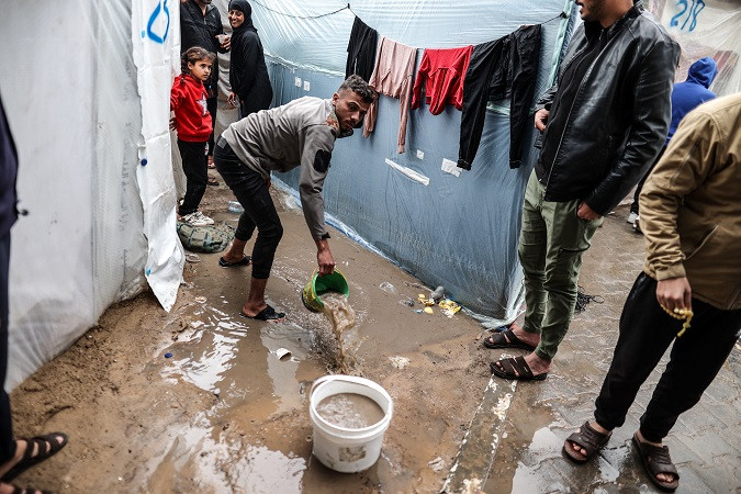 Người Palestine trú mưa tại một trại dành cho người di tản ở Rafah, miền nam Gaza