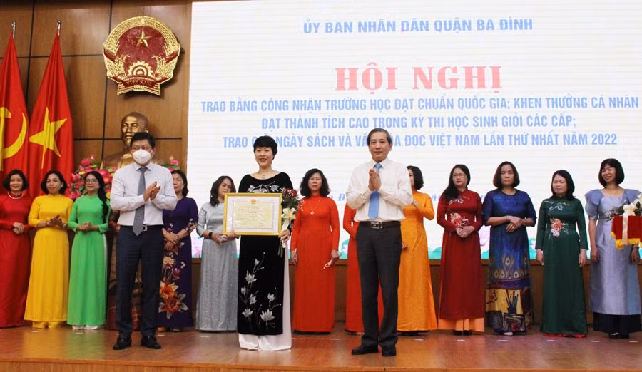 Bí thư Quận ủy Hoàng Minh Dũng Tiến (bên phải) và Chủ tịch UBND quận trao bằng khen cho giáo viên. 