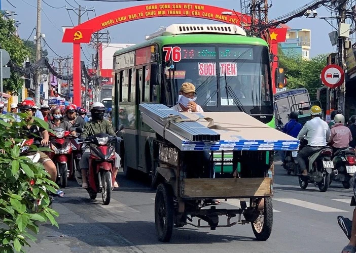 Một xe ba gác thô sơ đang vận chuyển hàng trên đường phố TPHCM.