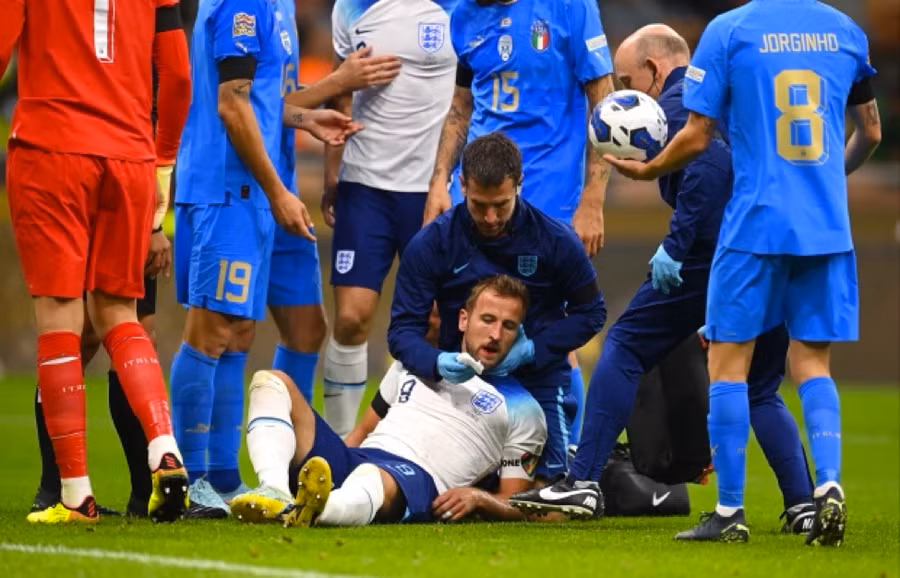 Máu chảy ra từ miệng Kane và đang được các nhân viên y tế chăm sóc.