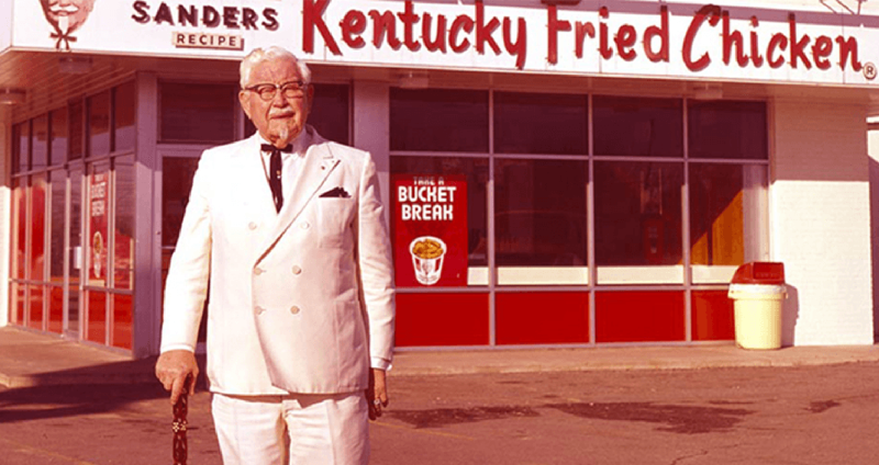 Đại tá Sanders đứng trước một nhà hàng KFC Đại tá Sanders đứng trước một nhà hàng KFC