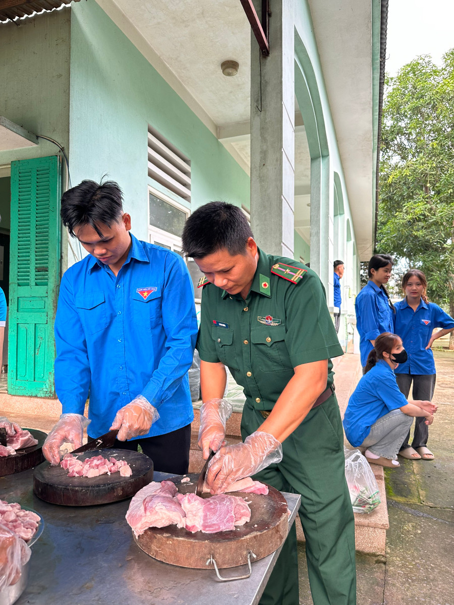 Tình nguyện viên đang thái thịt lợn chế biến món ăn hỗ trợ các học sinh.