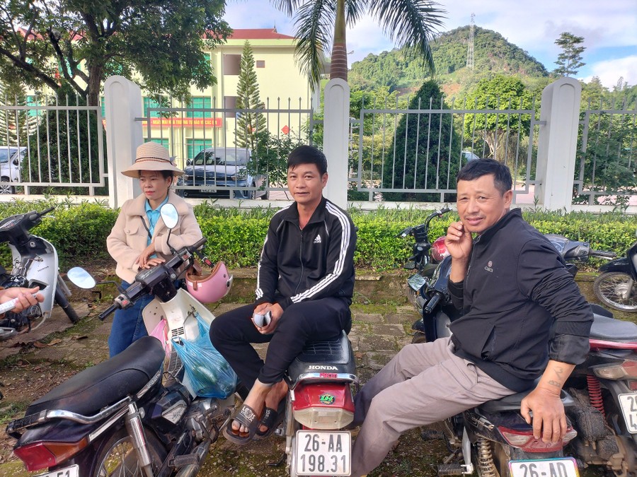 Phụ huynh học sinh ngồi ngoài cổng chờ con thi môn Toán.