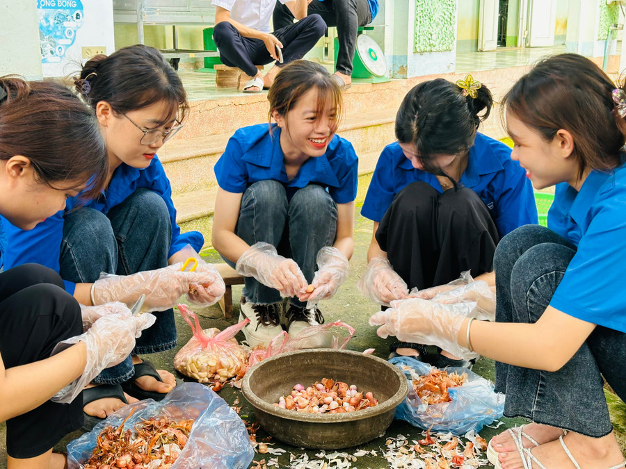 Các tình nguyện viên đang bóc hành chế biến thức ăn hỗ trợ học sinh.
