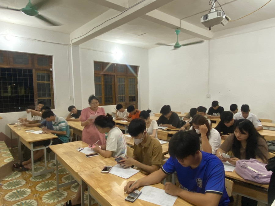 Cô Dân đang dạy phụ đạo kiến thức cho học sinh vào ban đêm. Cô Dân đang dạy phụ đạo kiến thức cho học sinh vào ban đêm.