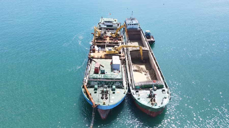 Tàu Đức Thịnh 88 (bên trái) dùng hệ thống máy bơm để bơm nước từ biển lên khoang tàu trộn với các vật liệu nạo vét vừa múc từ con tàu ký hiệu TRANCO 18 - Vr15038053, NĐ-4096 để bơm lên bãi thải của Dự án nạo vét giai đoạn 2 khu vực kênh xả, kênh nhập nước làm mát Nhà máy Nhiệt điện Vũng Áng II tại xã Kỳ Lợi. (Ảnh: T.H)