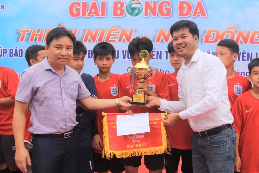 Ông Hoàng Xuân Hùng - Phó Chủ tịch UBND huyện Đức Thọ và nhà báo Nguyễn Văn Dũng trao cúp cho đội tuyển giành chức vô địch khối THCS.