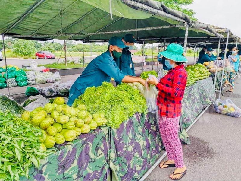 Các chiến sĩ lực lượng vũ trang Quận 12 đang hướng dẫn người dân nhận rau củ. Ảnh: Trang tin điện tử Đảng bộ TP.HCM.