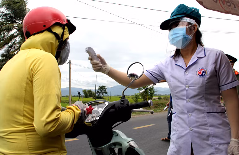 Nhân viên y tế huyện Tây Hòa, Phú Yên kiểm tra thân nhiệt cho người có đủ điều kiện qua chốt kiểm dịch Covid-19. Ảnh: Thanh Lê.