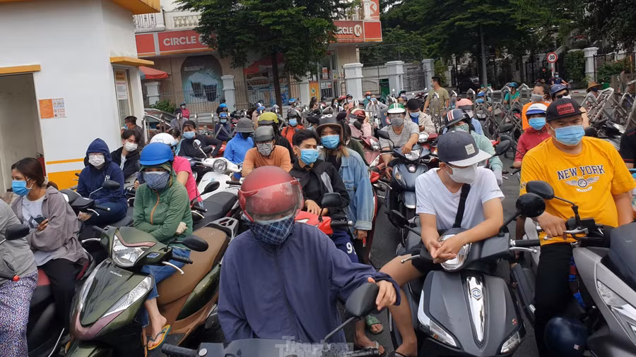 Dù trời đổ mưa nhưng rất đông người dân vẫn cố gắng đứng xếp hàng dài cả trăm mét từ trong cổng siêu thị Emart ở quận Gò Vấp, TP Hồ Chí Minh ra ngoài đường để đợi vào mua hàng. Nguồn: TPO.